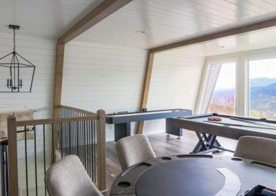 upstairs loft of a cabin with pool table, shuffleboard, and game table. Window overlooks the Smoky Mountains